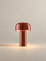 Portable dome lamp in Brick Red, light on, warm neutral studio